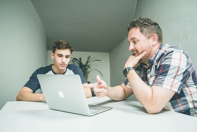 Two men staring at a laptop screen.